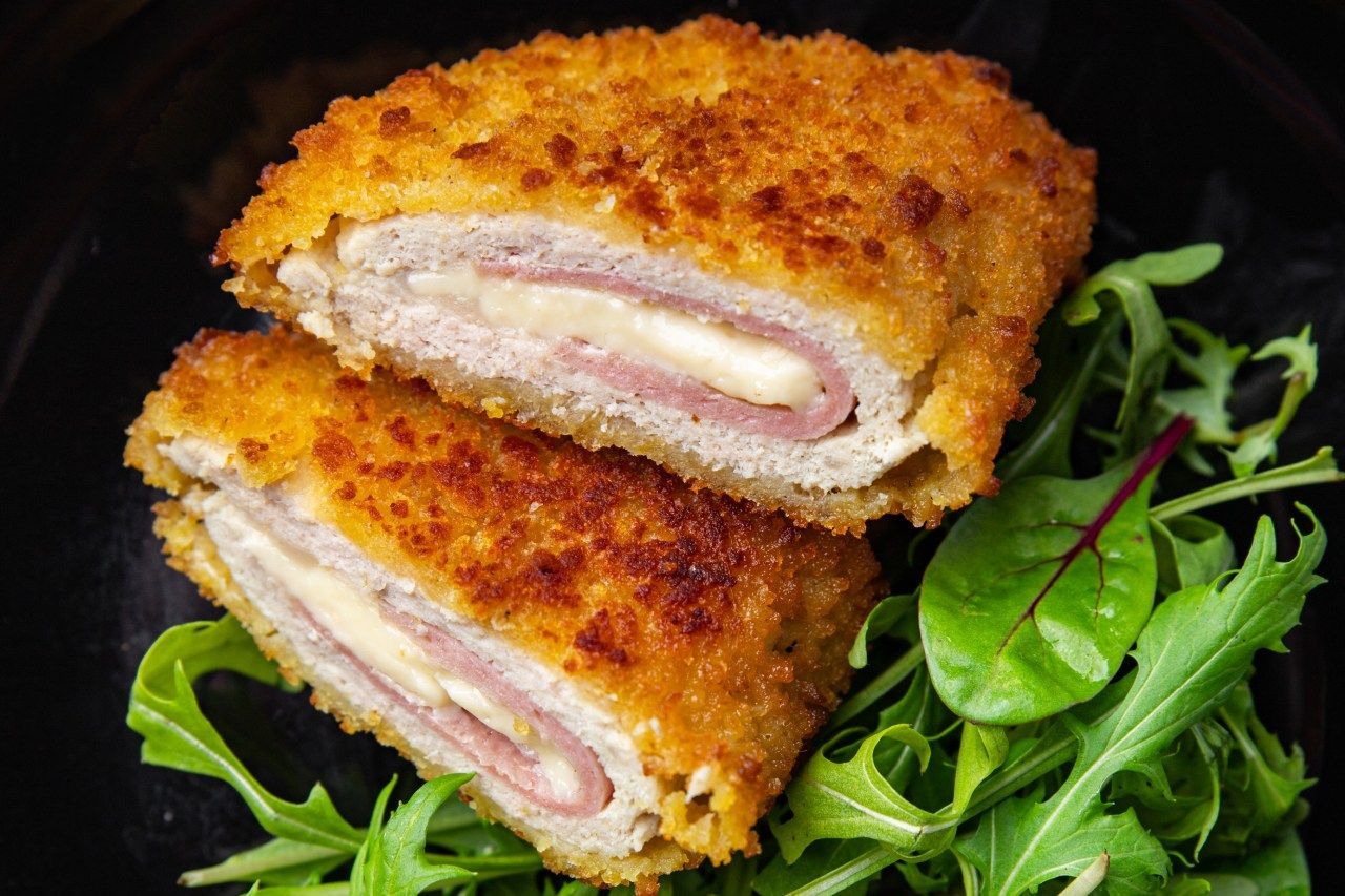 Dois pedaços de frango cordon bleu em um prato com alface.