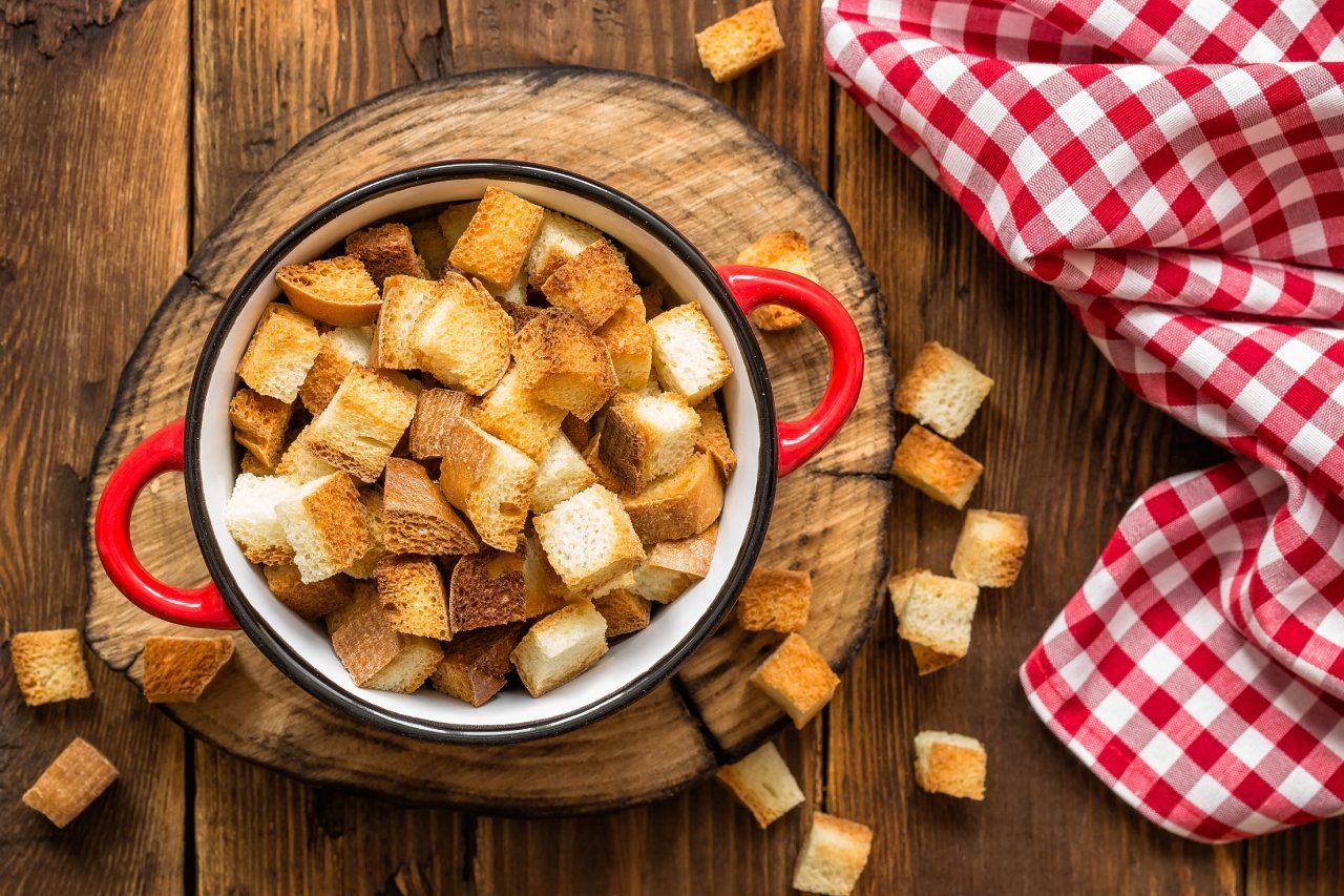 Uma tigela de croutons está sobre uma mesa de madeira.
