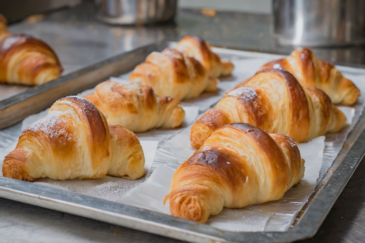 Uma bandeja de croissants cobertos com açúcar de confeiteiro sobre uma mesa.