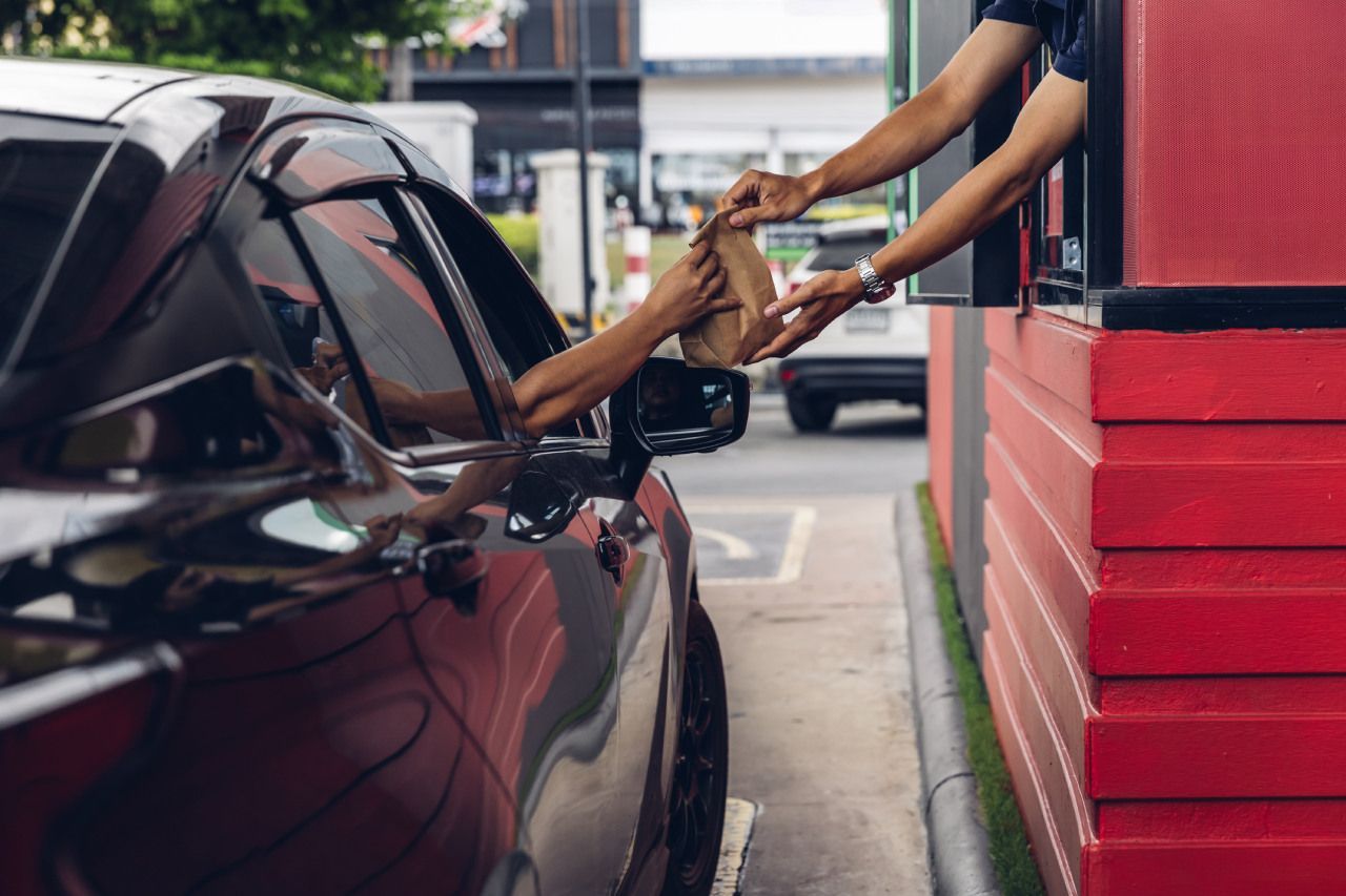 cliente pegando encomenda de comida em um drive-thru