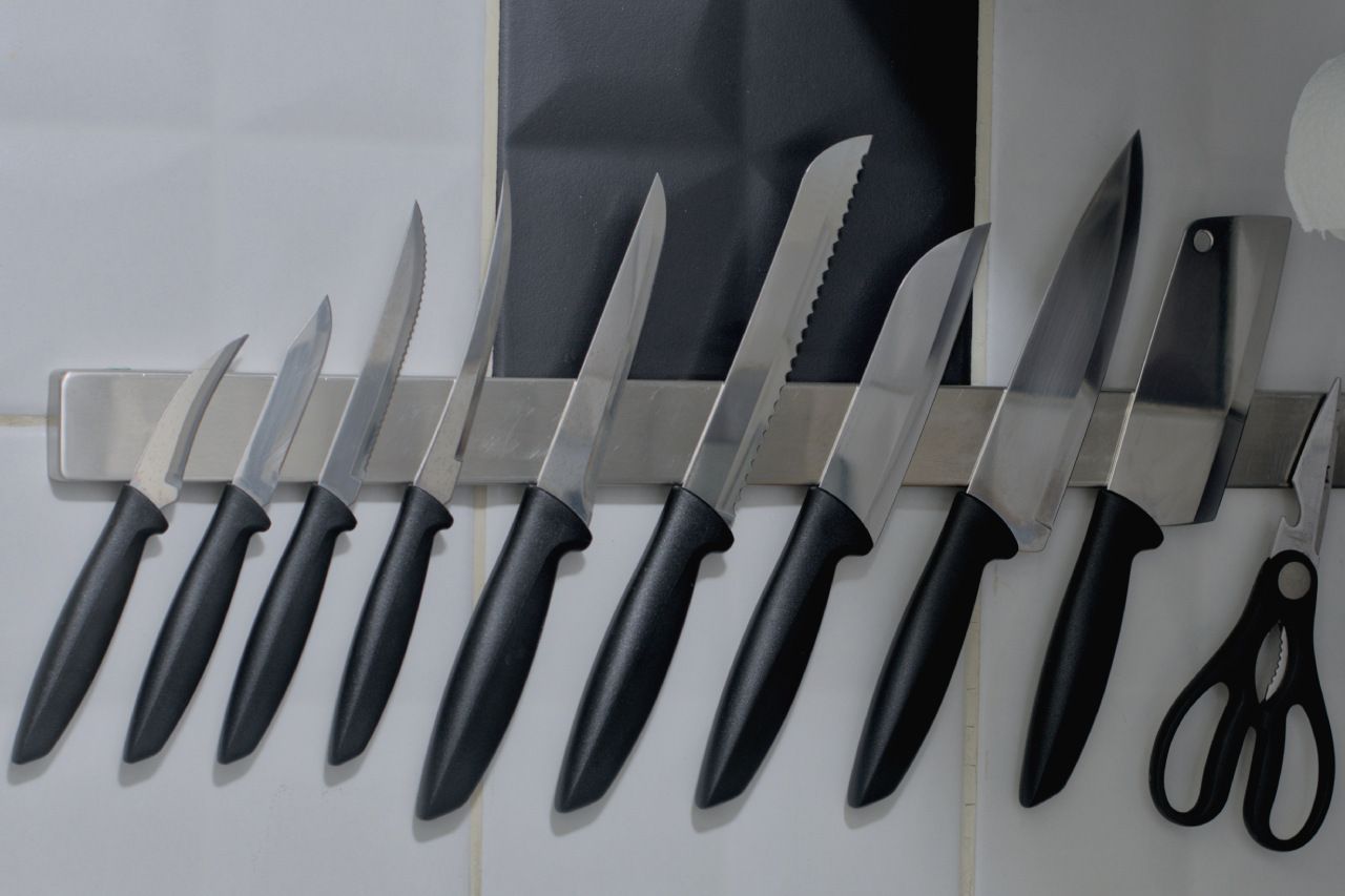 Uma fileira de facas e tesouras penduradas na parede