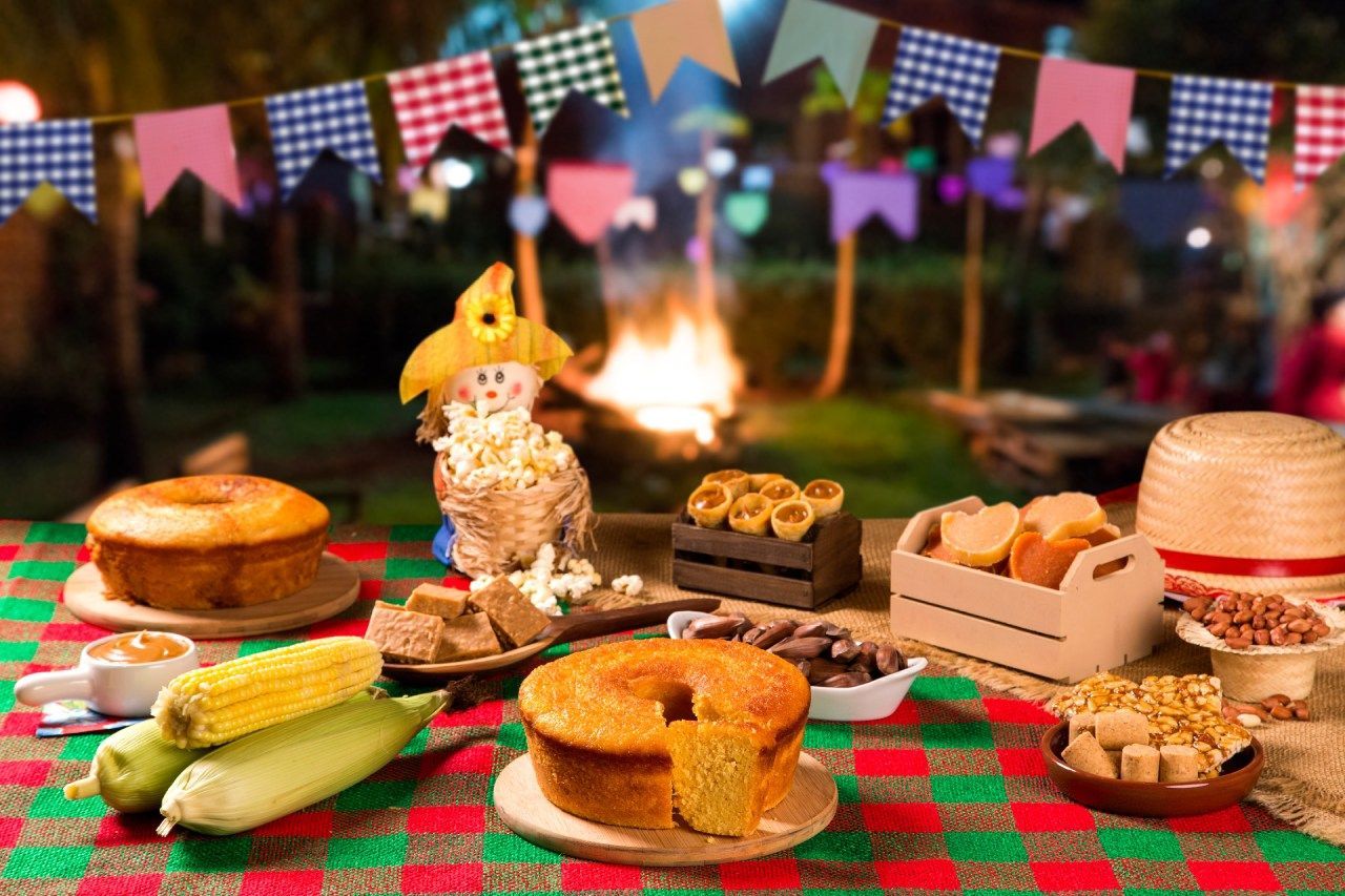 Mesa decorada com tema festa junina e julina com bolo de fubá, milho e doces