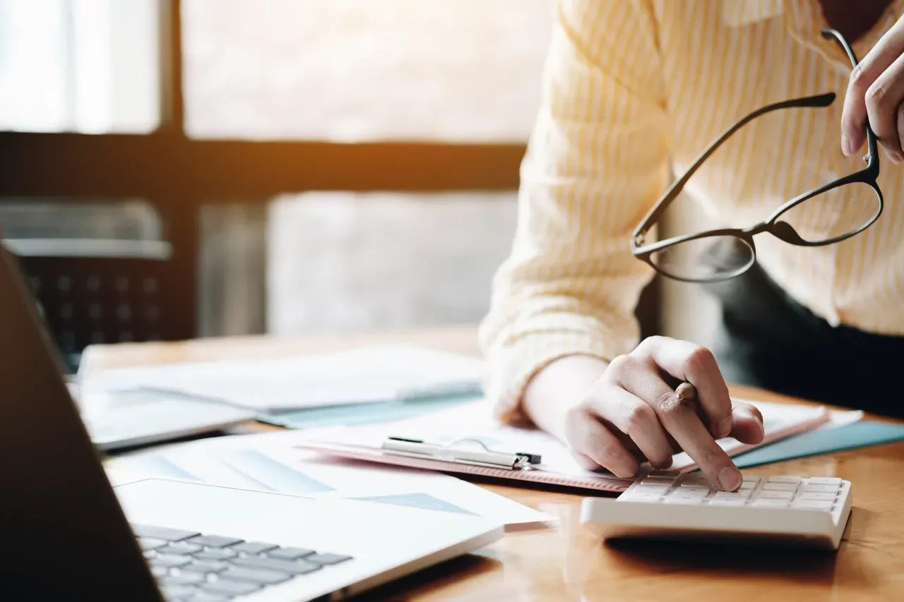 Pessoa usando calculadora e analisando gráficos financeiros.