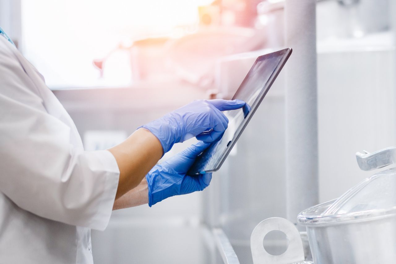 Um cientista usando luvas azuis está usando um tablet em um laboratório.