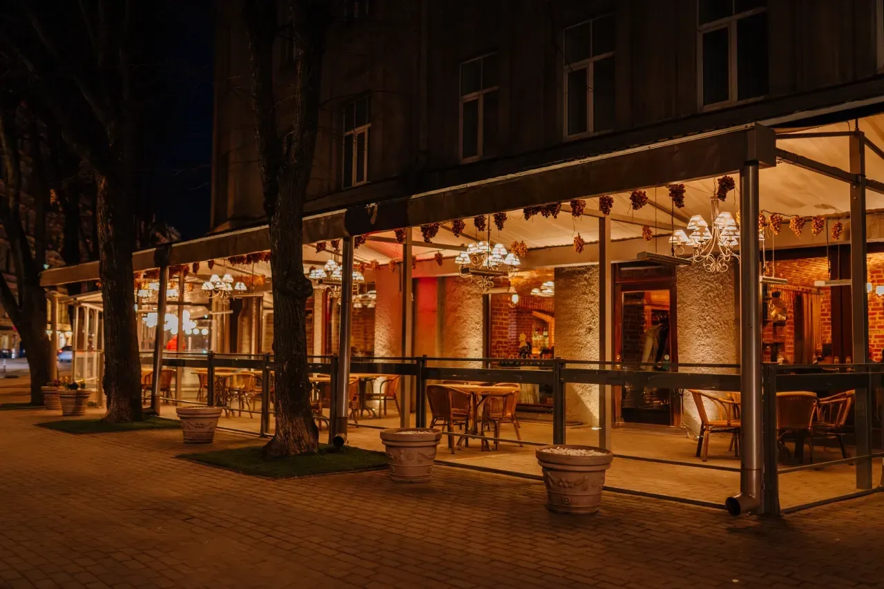 Um restaurante com mesas e cadeiras é iluminado à noite.