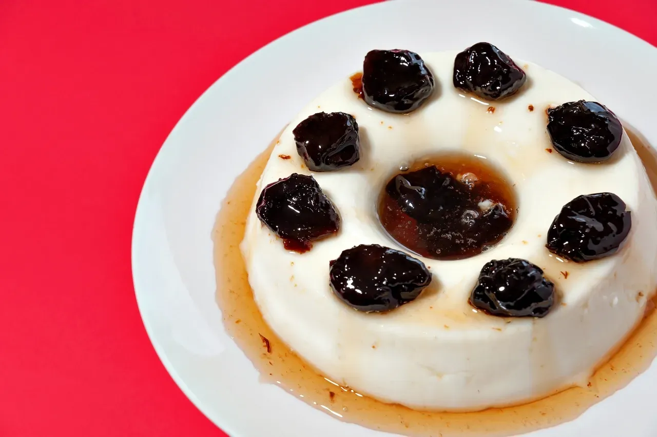 Um prato branco coberto com uma sobremesa com passas e calda