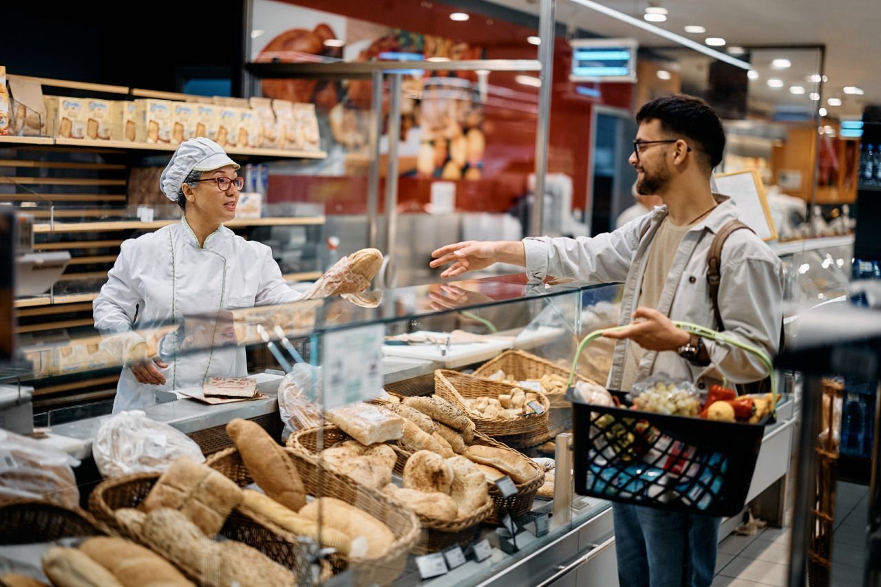 atendente entregando pão para cliente em loja de supermercado