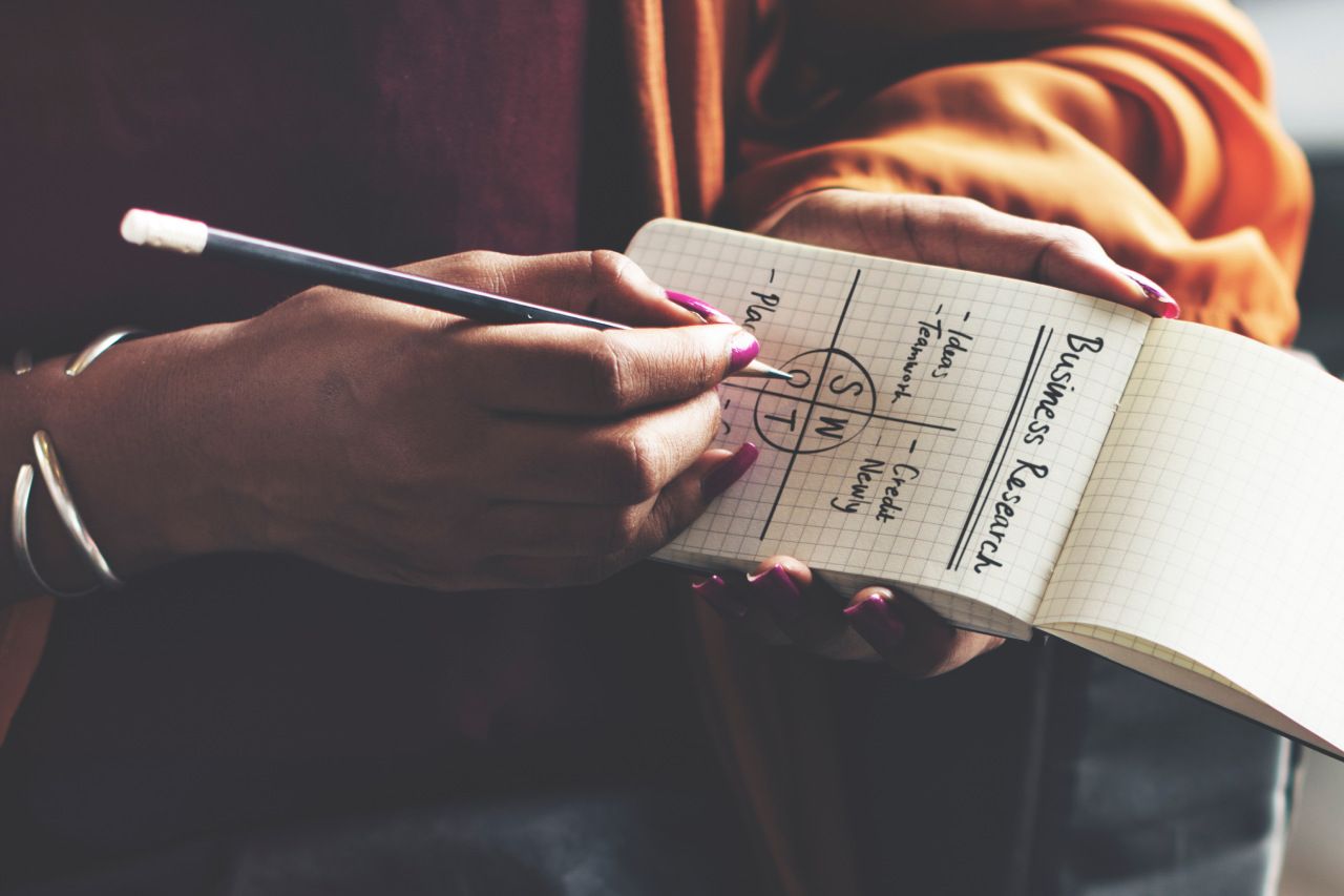 Uma mulher está escrevendo em um caderno com um lápis.