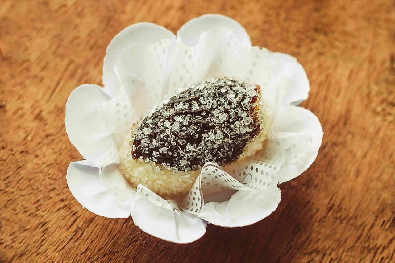 Um close de um doce olho de sogra em uma embalagem em forma de flor sobre uma mesa de madeira.