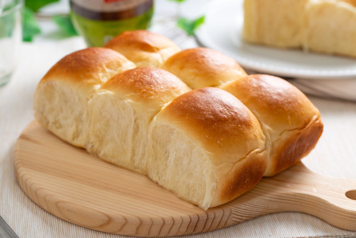 Um pedaço de pão está sobre uma tábua de corte de madeira.