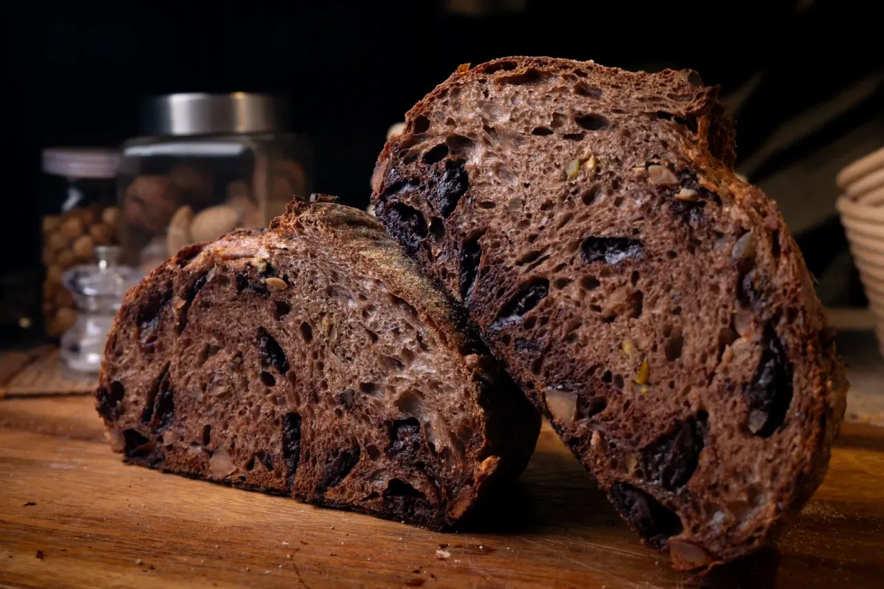 Duas fatias de pão de chocolate estão sobre uma tábua de corte de madeira.