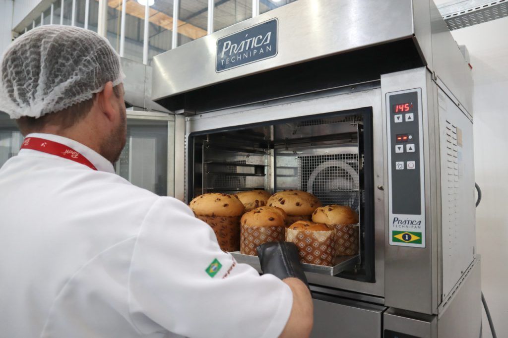 Um homem está tirando um monte de bolos do forno.