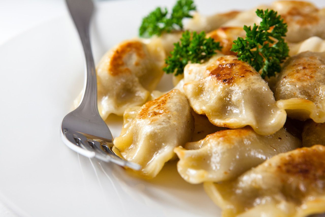 Um prato de pierogis com salsa e um garfo sobre uma mesa.