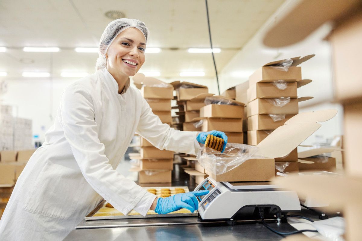 Uma mulher de jaleco está trabalhando em uma fábrica.