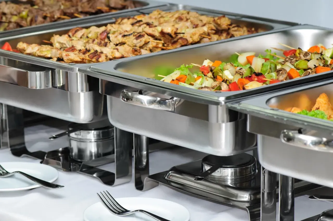 Rechaud de comida em buffet mantendo alimentos quentes em cubas inox