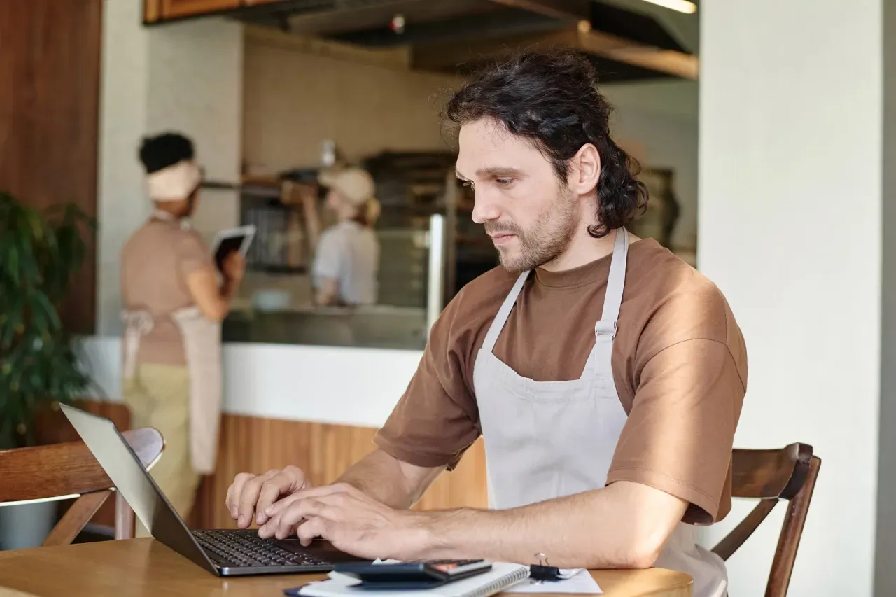 Um homem está sentado à mesa usando um laptop.