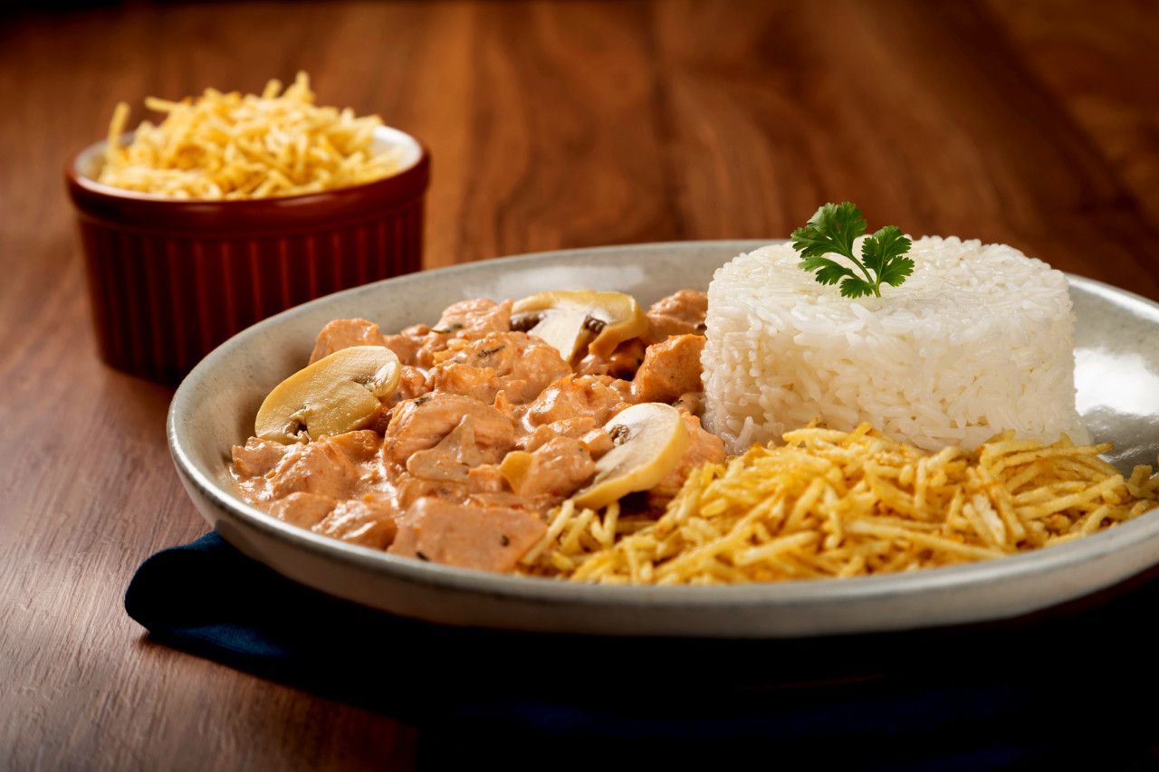 Um prato de comida com arroz e macarrão em uma mesa de madeira.