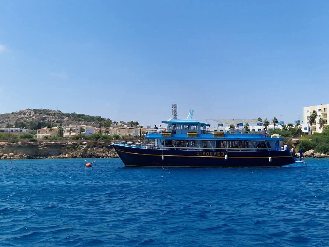 A large blue boat is floating on top of a large body of water.