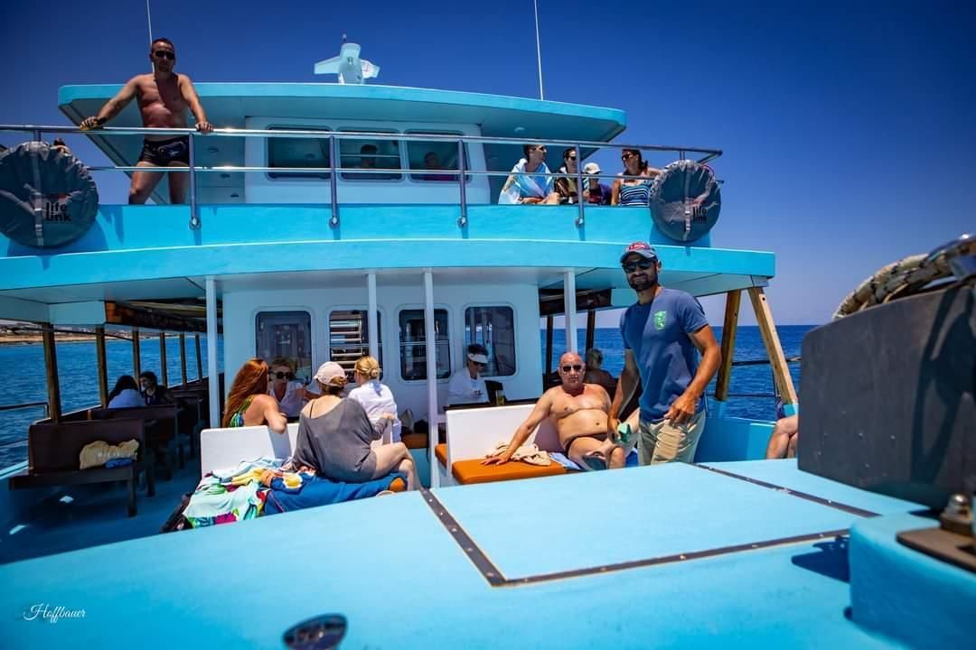 A group of people are sitting on the deck of a boat in the ocean.
