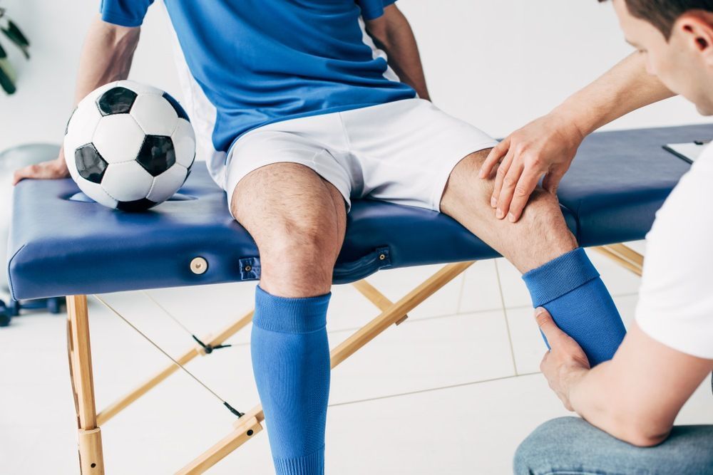 Soccer Player Getting a Knee Exam by A Therapist on A Massage Table — Axis Chiropractic In Cairns City, QLD