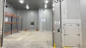 a large empty room with shelves and a door. Industrial Cold Storage