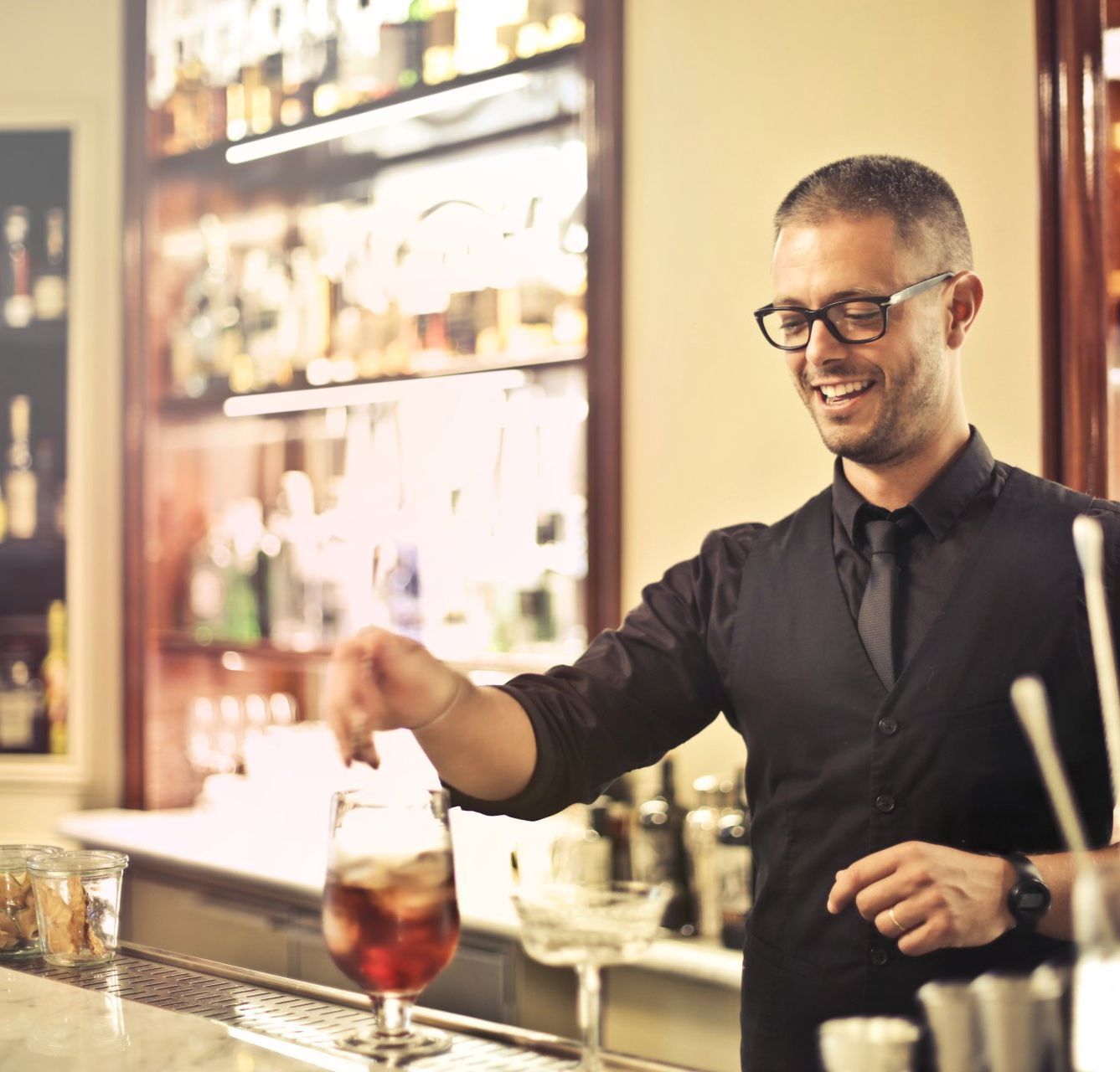 a bartender is pouring a drink into a glass.  