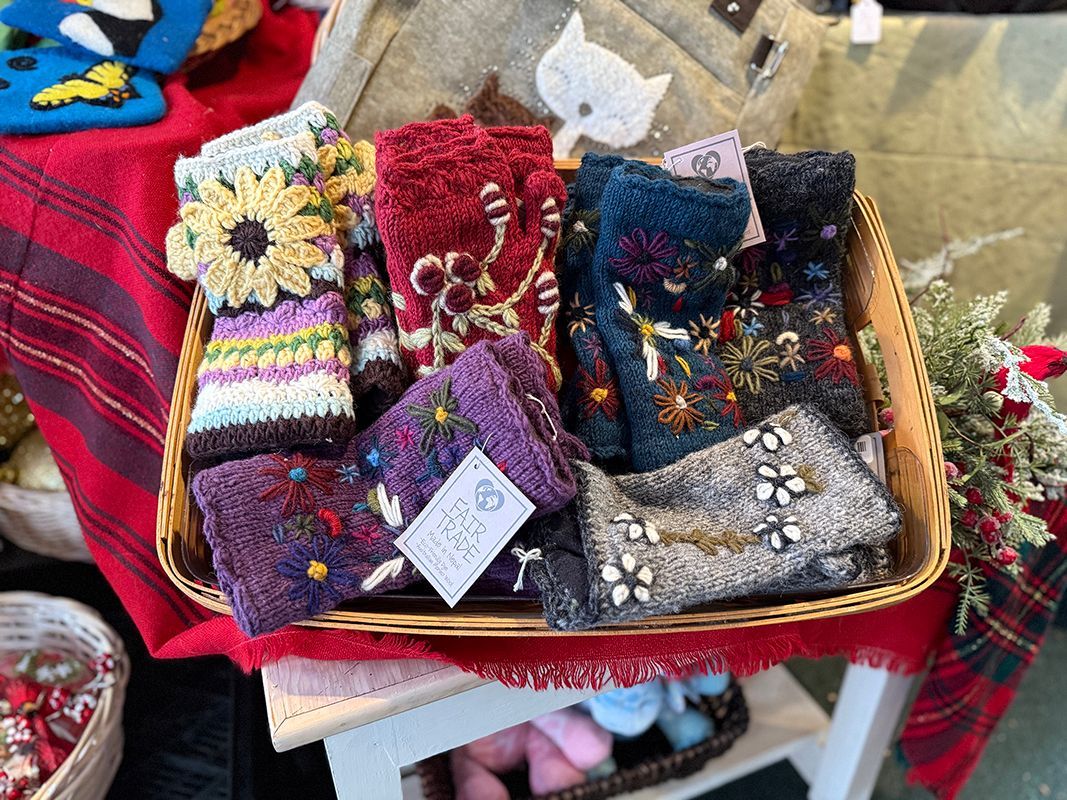 Basket of colorful, embroidered fingerless gloves for sale.