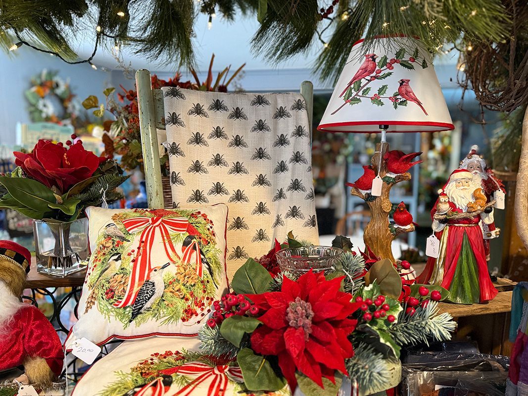 A cone filled with flowers and ferns is hanging on a wall next to potted plants.