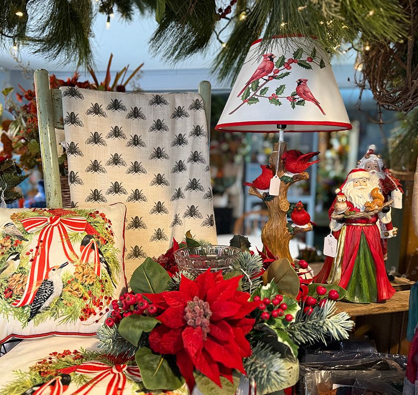 Christmas display with cardinals, poinsettias, Santa figurine, and patterned textiles.