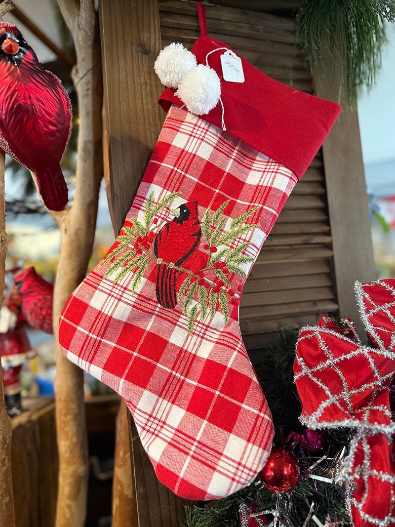 Christmas stocking with a red cardinal on a red and white plaid background, hanging with decorations.