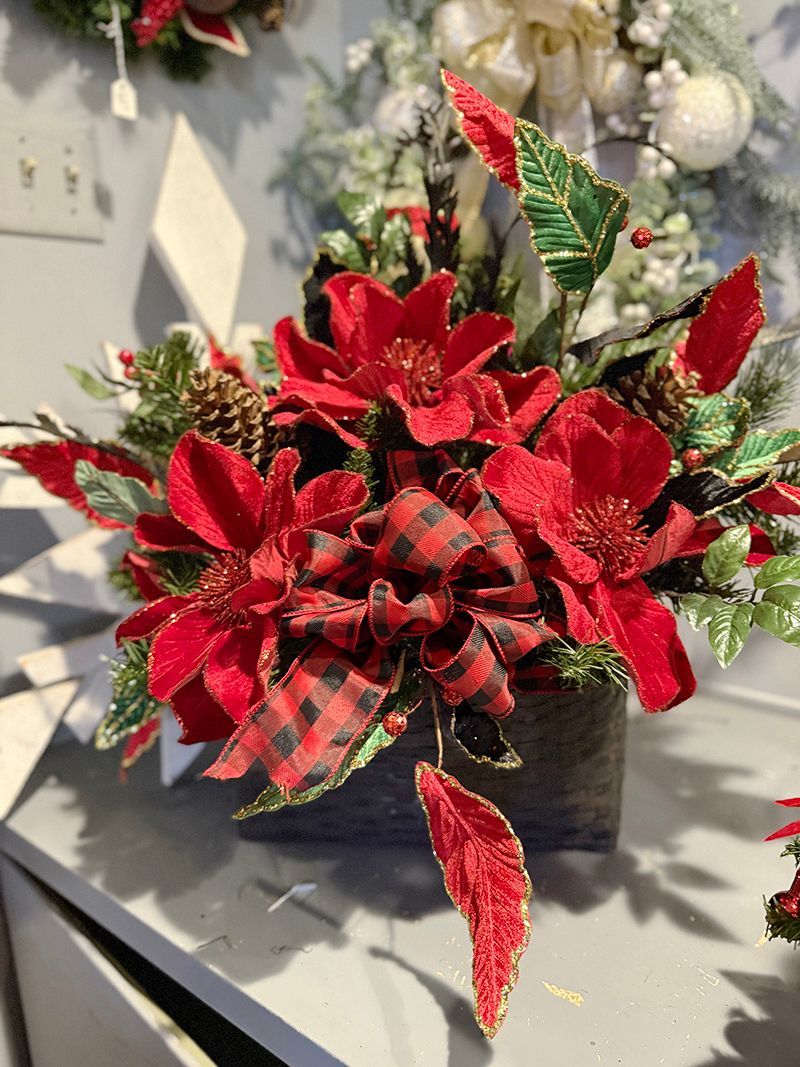 Red poinsettias and plaid bow floral arrangement in a dark rectangular vase.