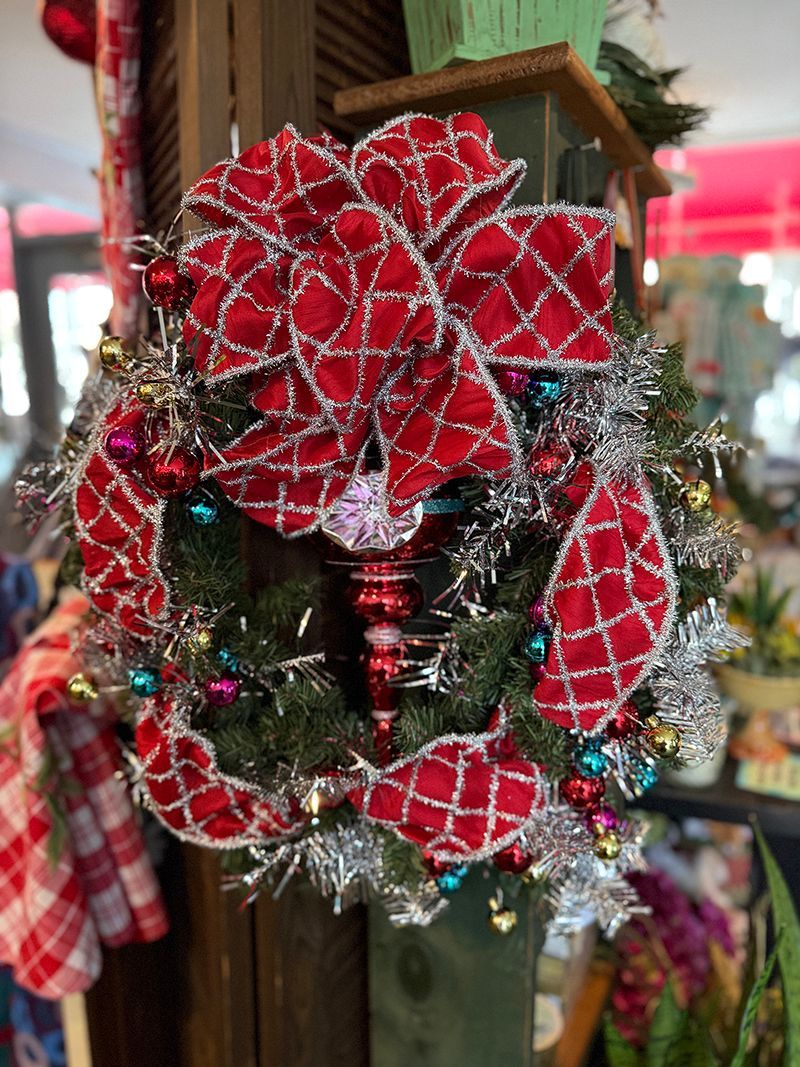 Christmas wreath with red bow and ornaments, decorated with silver tinsel.