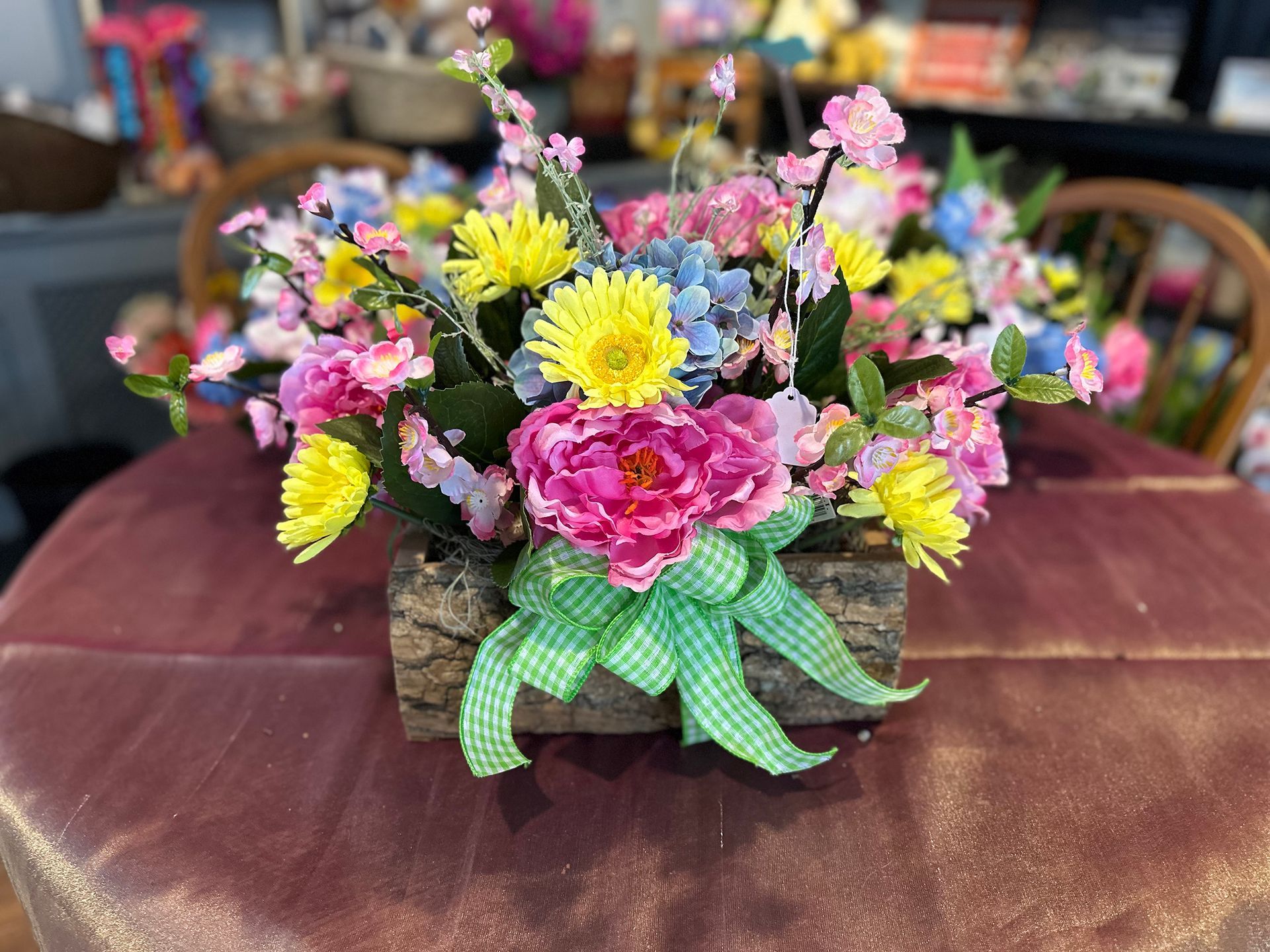 A wooden planter filled with colorful flowers is sitting on a table.