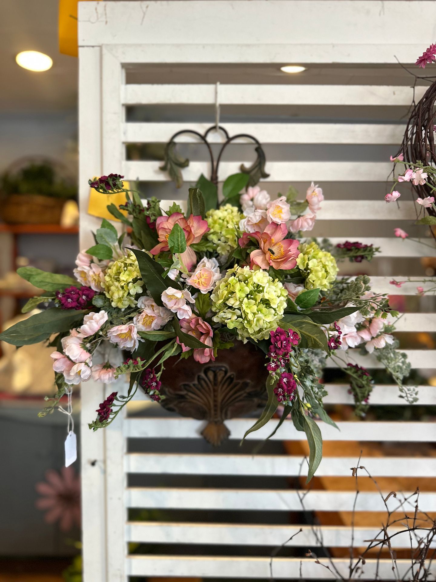 A hanging basket filled with flowers is hanging on a white fence.