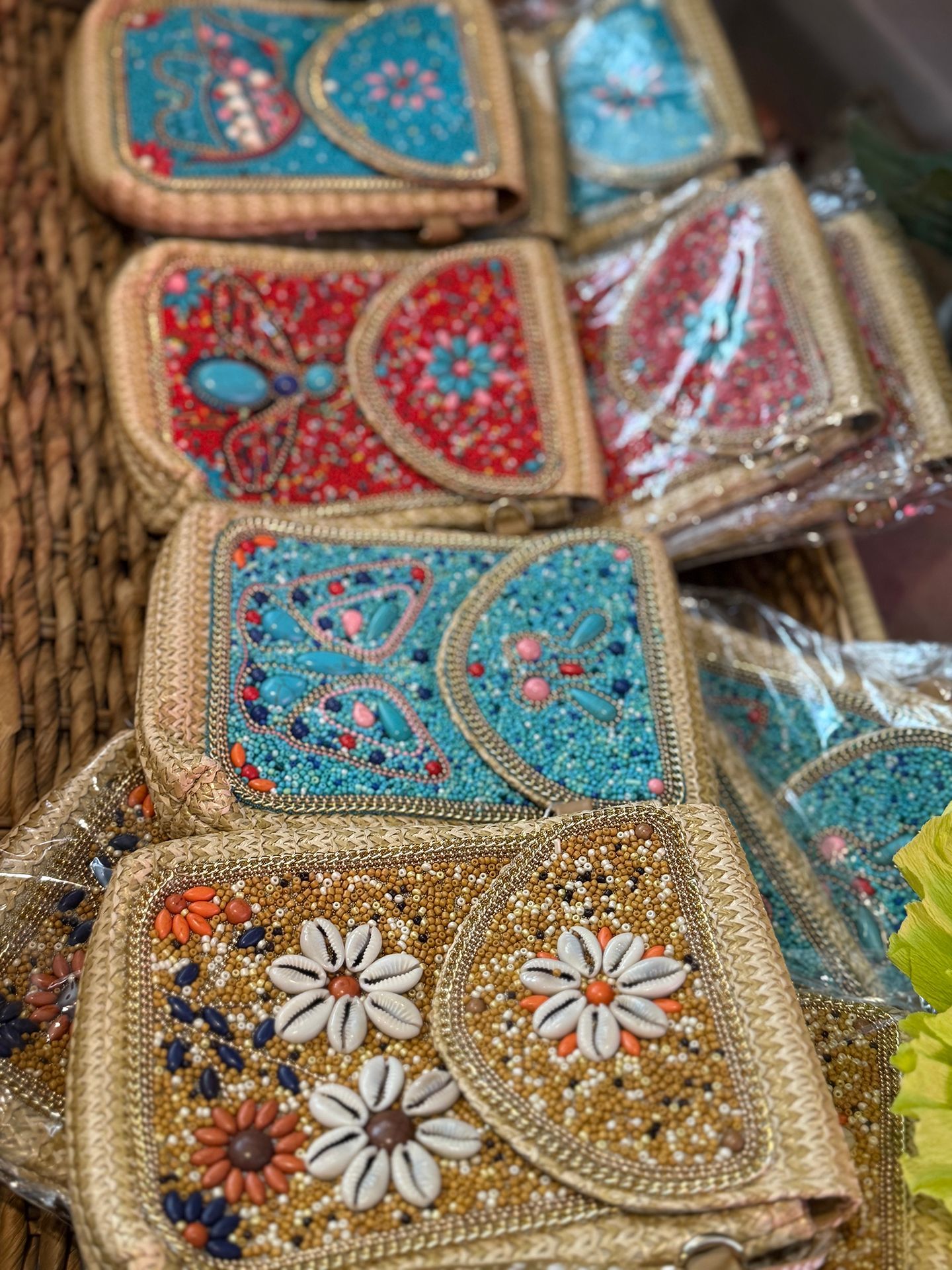 Beaded clutch purses in various colors including red, turquoise, and gold, displayed on a woven basket.