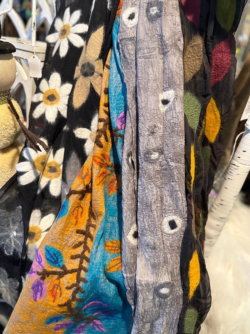 Close-up of five patterned fabric scarves, including floral and abstract designs, in shades of black, blue, and gold.