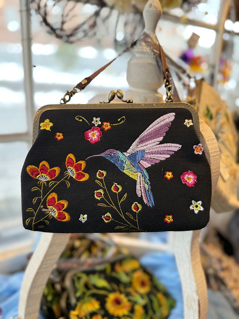 Black handbag with embroidered hummingbird and flowers.