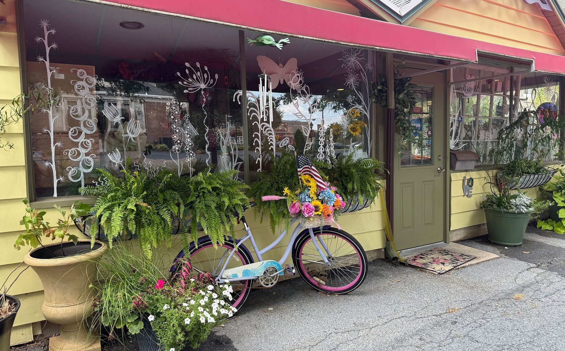 A yellow building with a red awning; a decorated bicycle with flowers sits in front of the entrance.