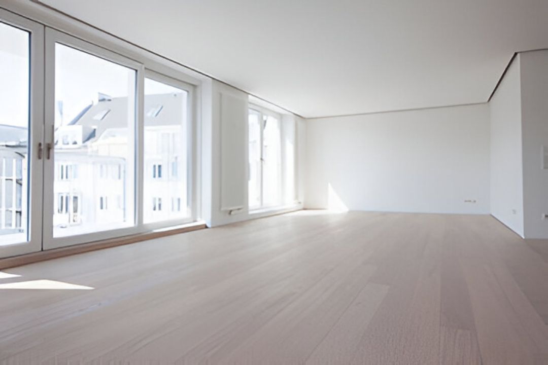 An empty living room with hardwood floors and lots of windows.