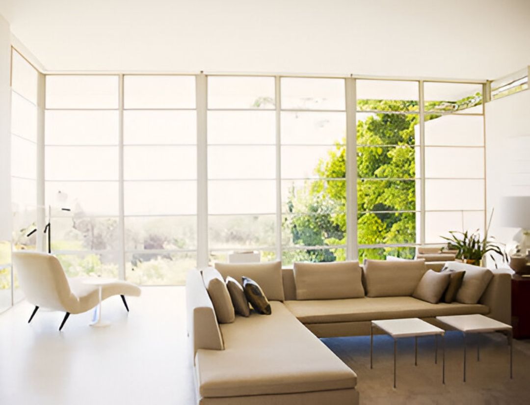 A living room with a couch , chair , table and large windows.