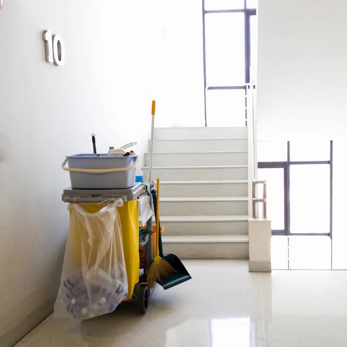 A woman wearing black gloves is cleaning a wooden table with a cloth.