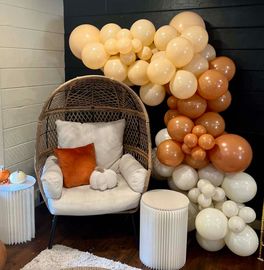 A chair is surrounded by balloons in a room.