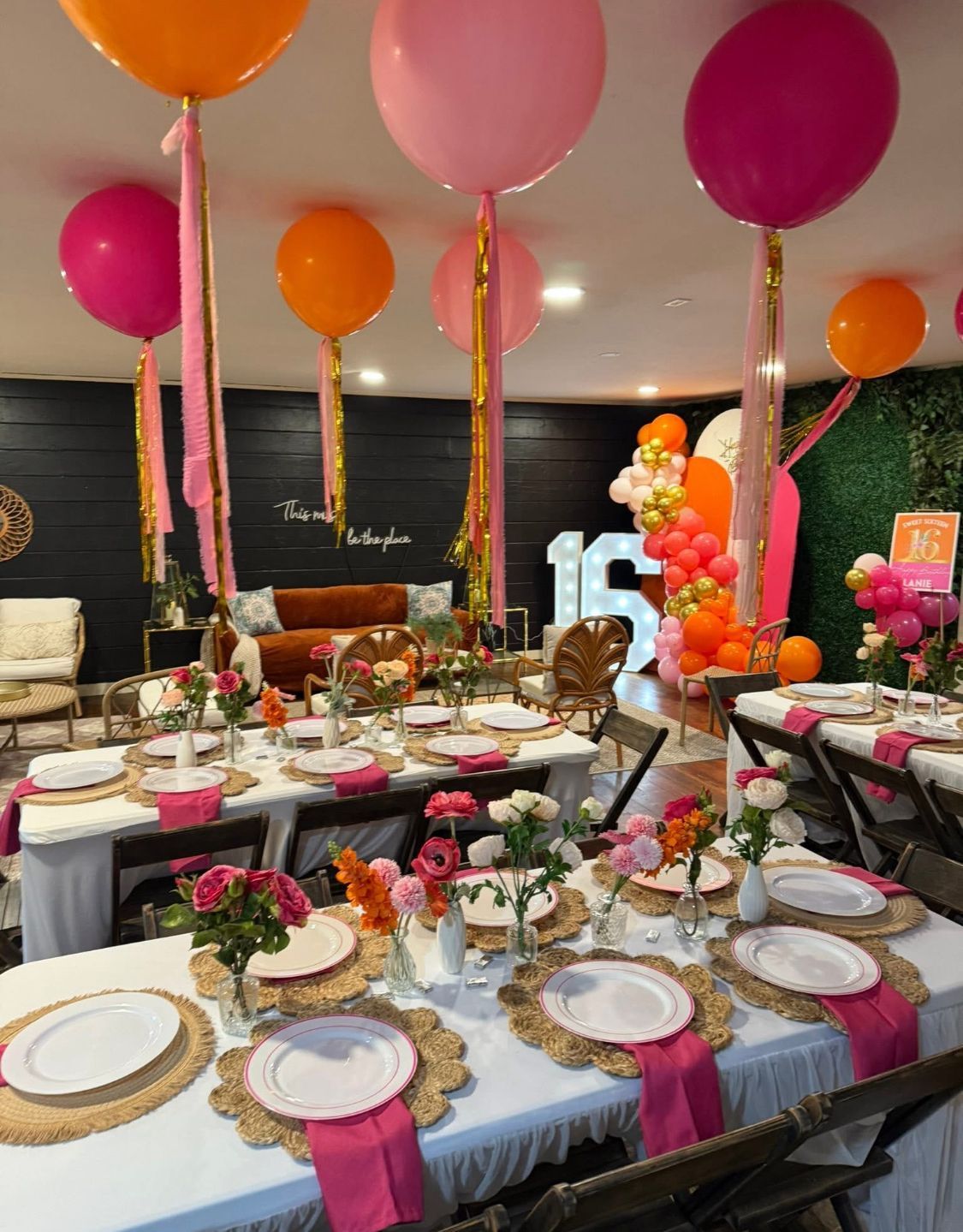 A chair is sitting under a balloon arch in a room.