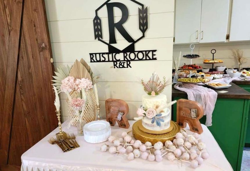 A table with a cake and a sign that says rustic rooke keir on it.