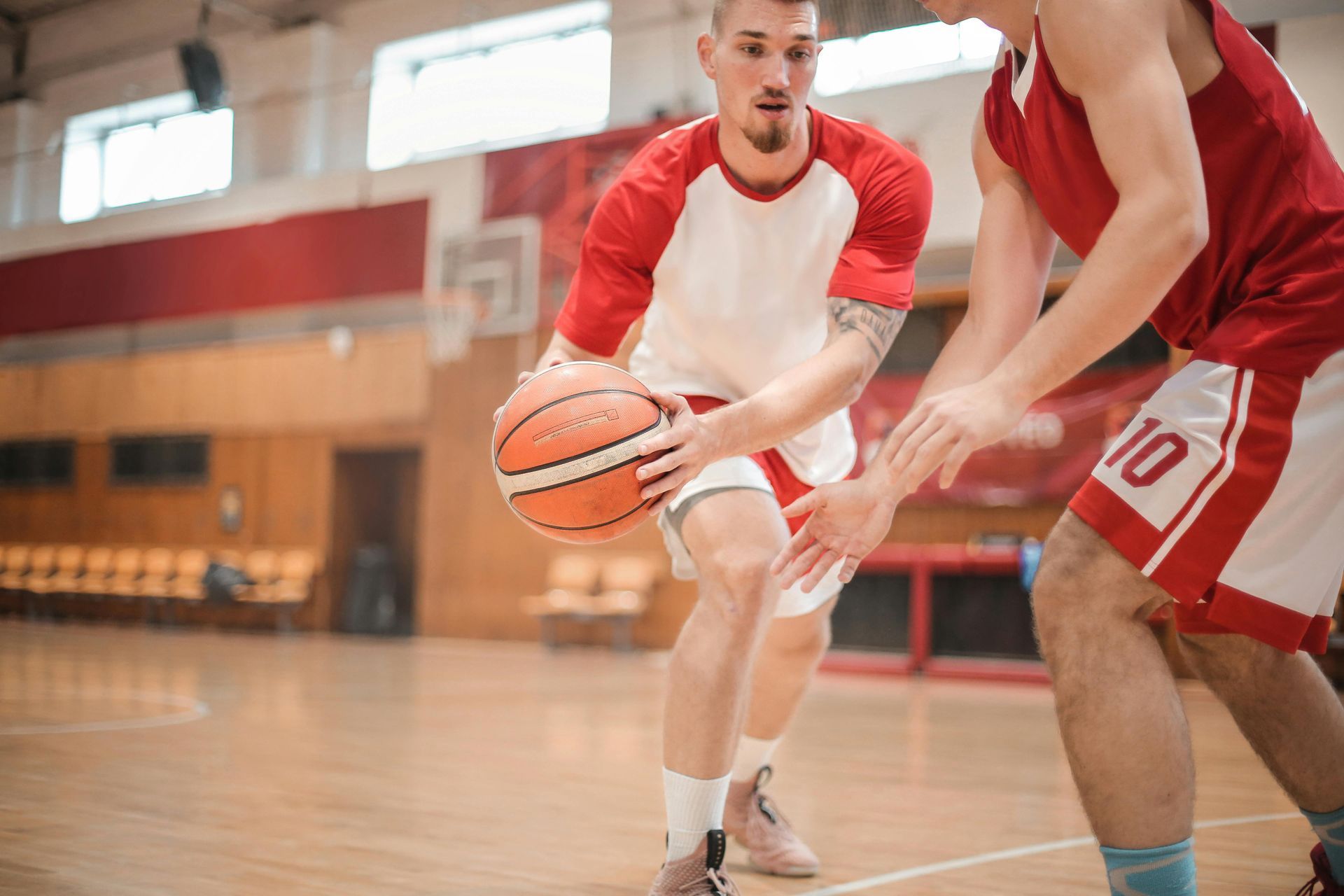 Basketball Players on a Wooden Court in Red and White Uniforms, Highlighting Professional AV Support for Sports Camps and Tournaments in Denver and Colorado Springs