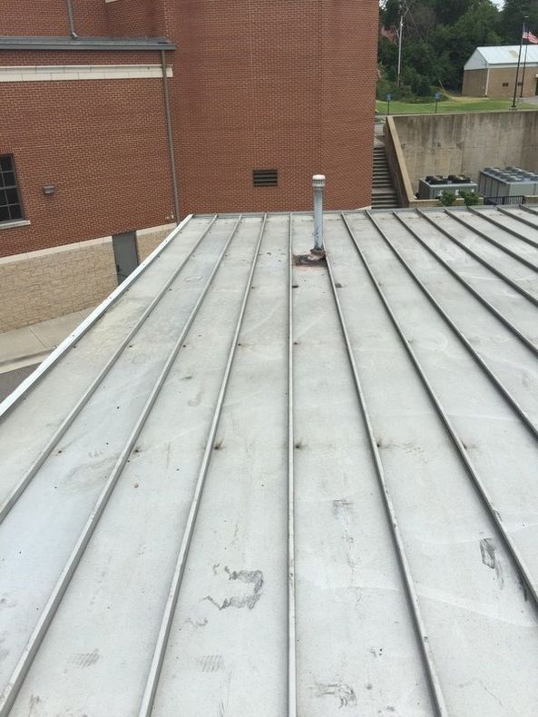 A metal roof with a brick building in the background