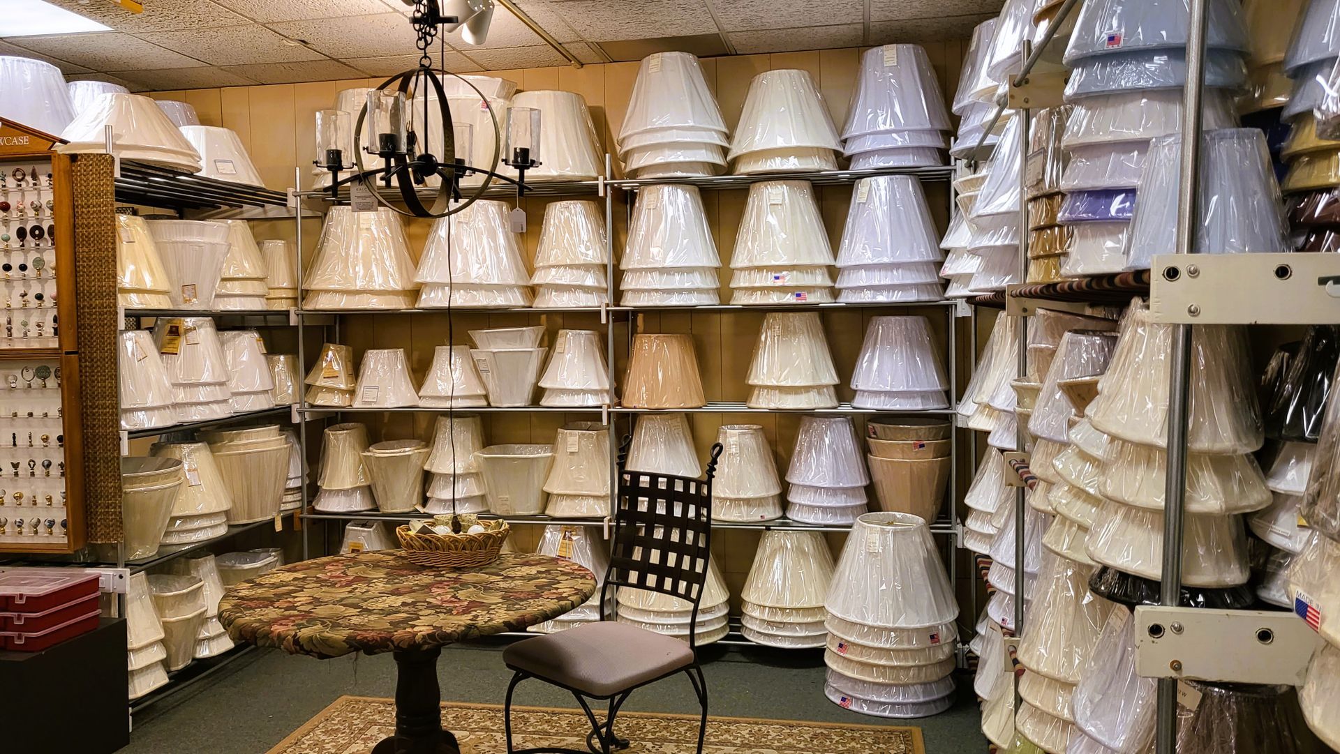 A room filled with lots of lampshades and a table and chair.