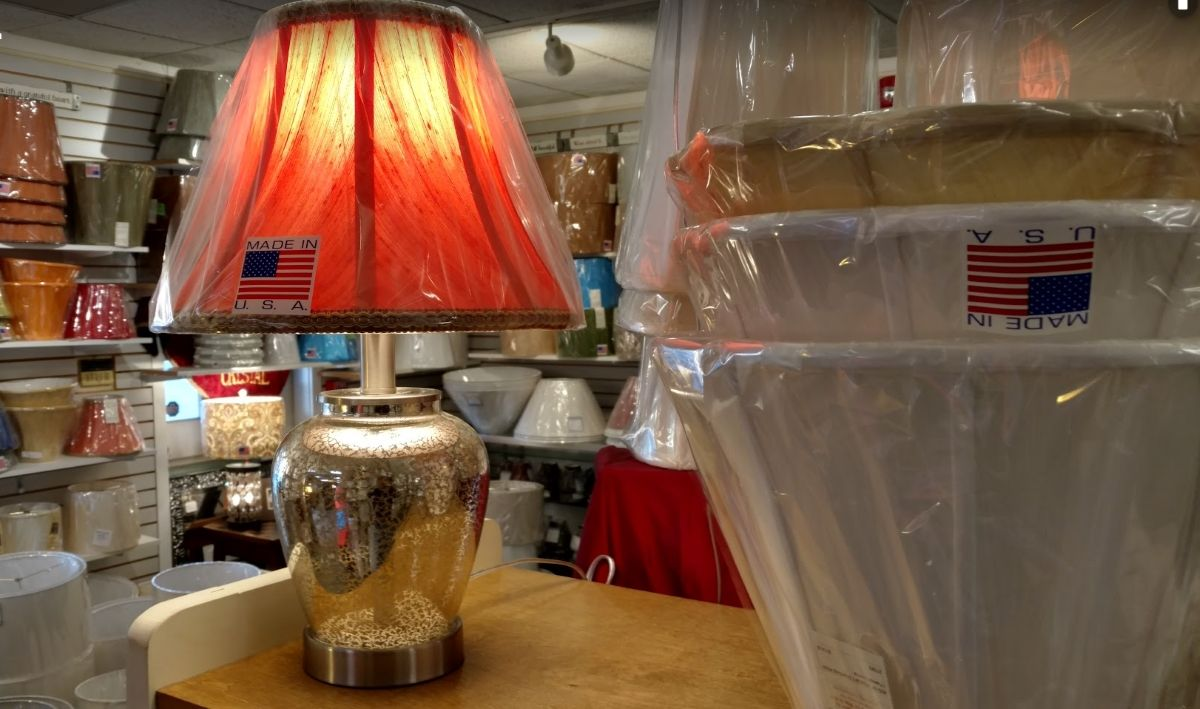 A lamp with a red shade is sitting on a table in a store.