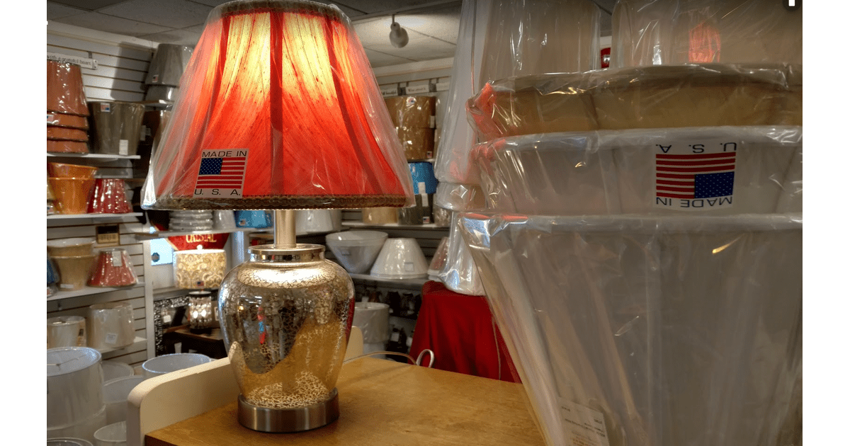 A lamp with a red shade is sitting on a table in a store.