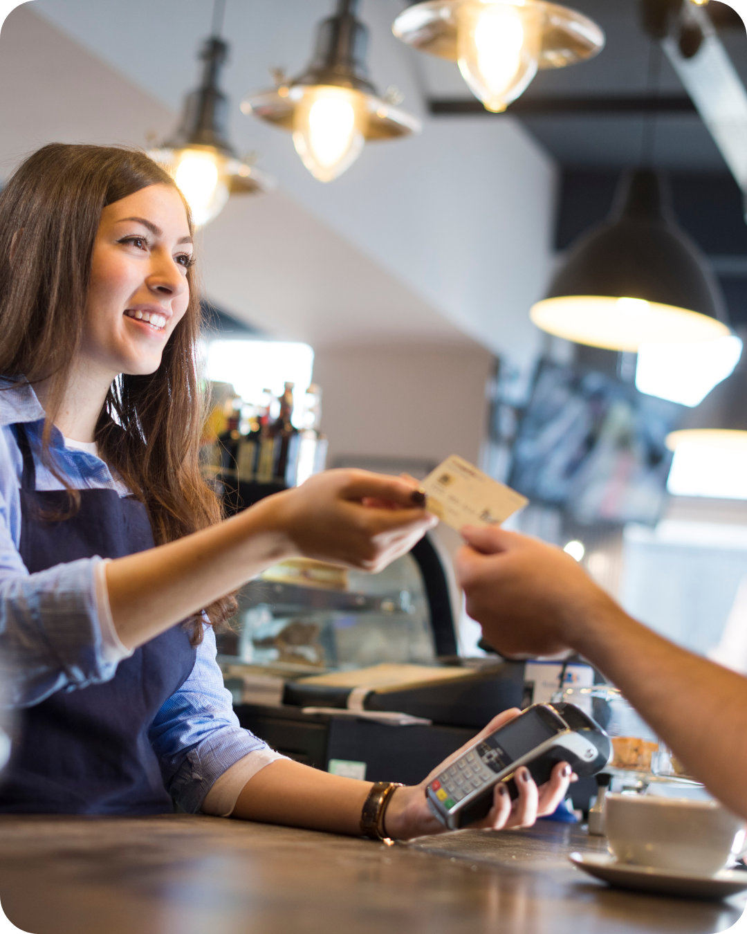 Una mujer le da una tarjeta de crédito a un hombre en un restaurante.